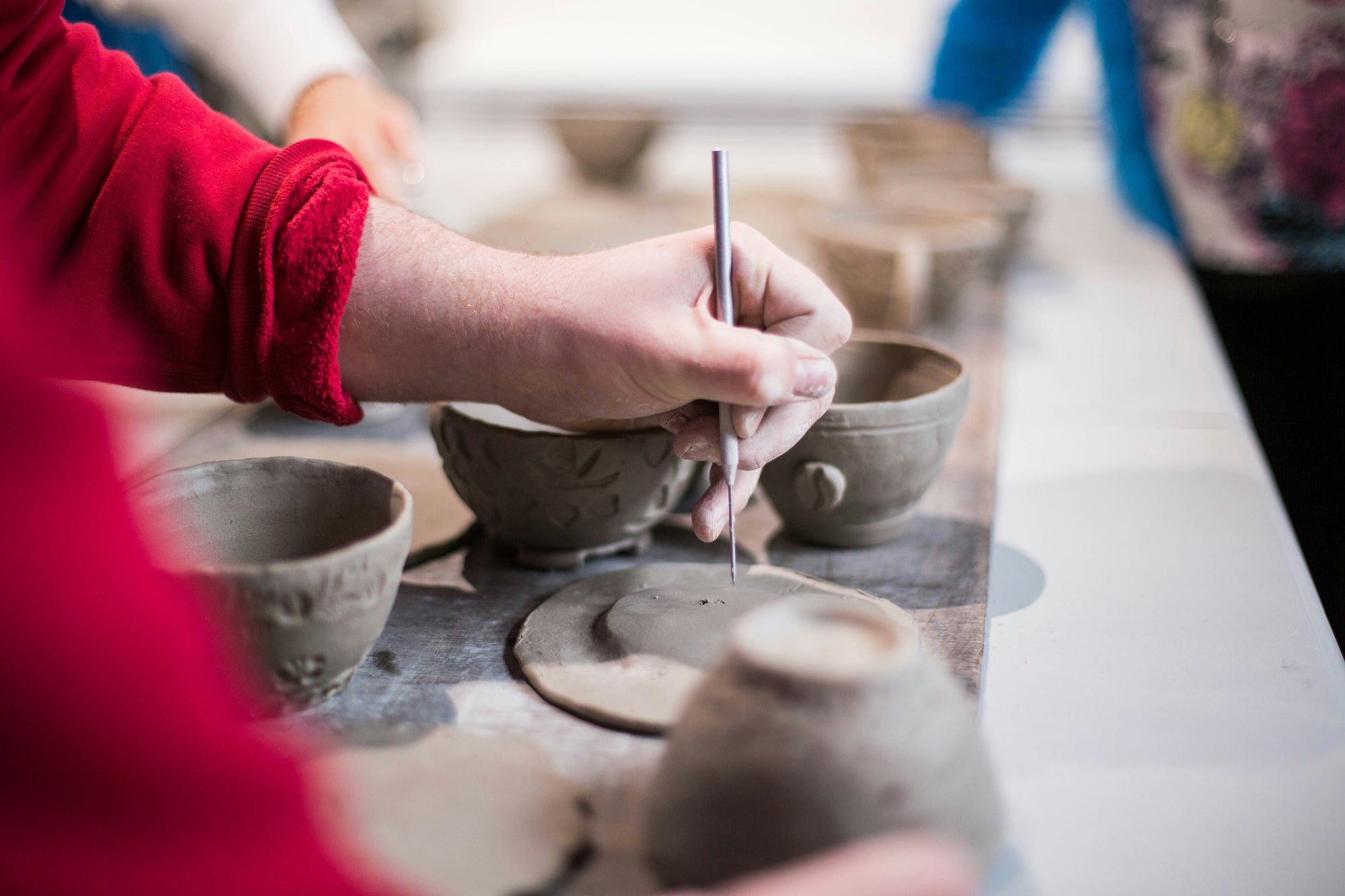 Person working with clay making cups win a studio workshop setting